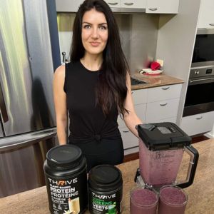 Woman in kitchen with Thrive Greens and Thrive Protein tubs