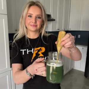 Woman mixing Thrive Ultimate Greens in a shaker bottle
