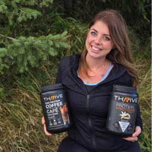 Woman holding two tubs of Thrive Protein Powder outdoors