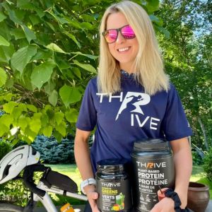 Customer holding Thrive Hydrate Blue Raspberry outdoors in sunglasses