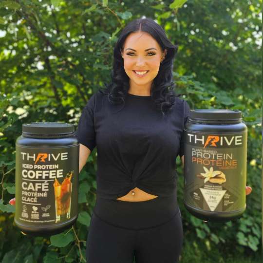 Woman holding Thrive Protein Powder two tubs outdoors
