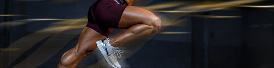 Close-up of a sprinter's legs mid-stride, muscles visibly engaged during high-intensity effort.