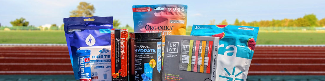 A selection of popular electrolyte powders and tablets, including Thrive Hydrate, Organika, LMNT, Nuun, BioSteel, Hydralyte, and Vega, arranged on a running track background.