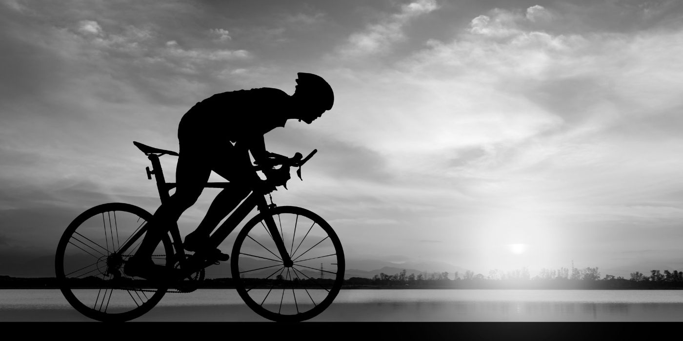 Silhouette of a cyclist against a dramatic sky with a setting sun.