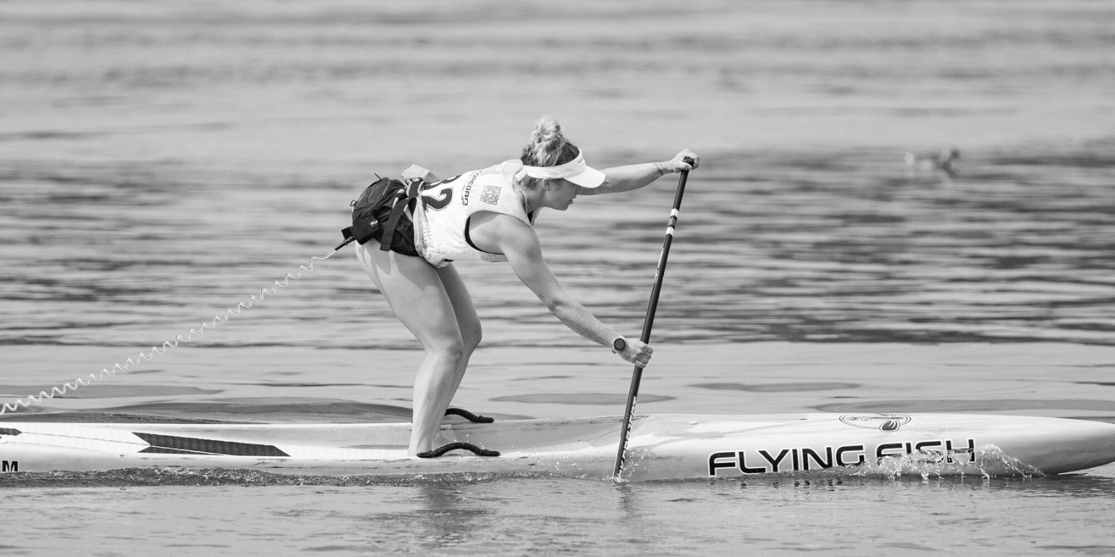Female athlete paddleboarding on open water, demonstrating strength, balance, and endurance supported by thrive protein for performance and recovery.