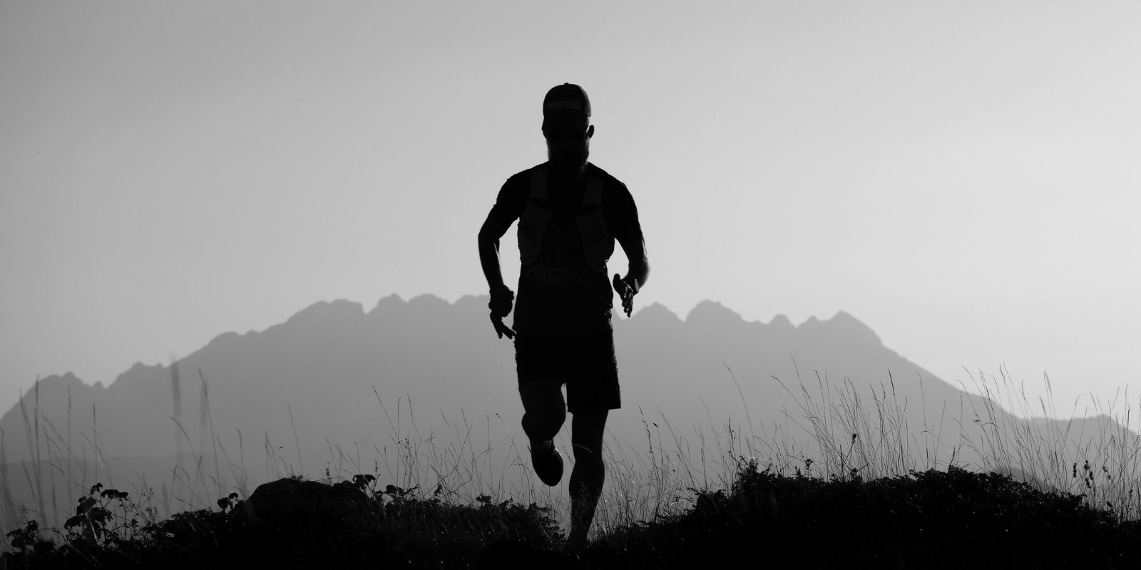 Silhouette of a man trail running at sunrise with mountains in the background, promoting Thrive Hydrate